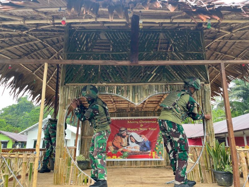 ‎Prajurit TNI berkolaborasi dengan warga, termasuk anak-anak, untuk membuat dan mendekorasi pohon Natal
