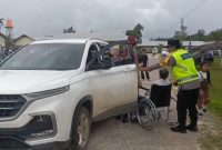 personel Polres Landak dengan penuh empati membantu seorang warga lanjut usia yang mengalami kelumpuhan dan menggunakan kursi roda untuk dapat melaksanakan ibadah Natal di gereja