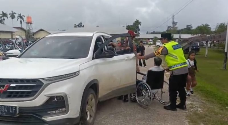 personel Polres Landak dengan penuh empati membantu seorang warga lanjut usia yang mengalami kelumpuhan dan menggunakan kursi roda untuk dapat melaksanakan ibadah Natal di gereja